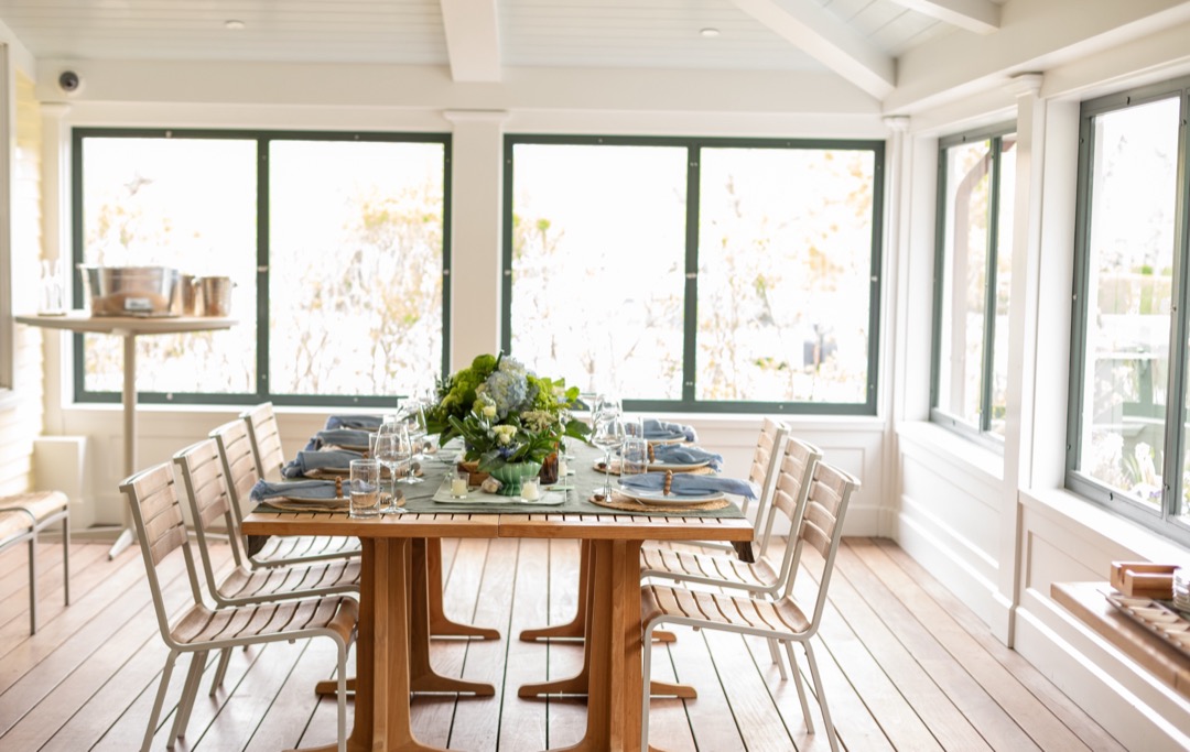 A long table set for a dinner on The Hive’s sunlit porch