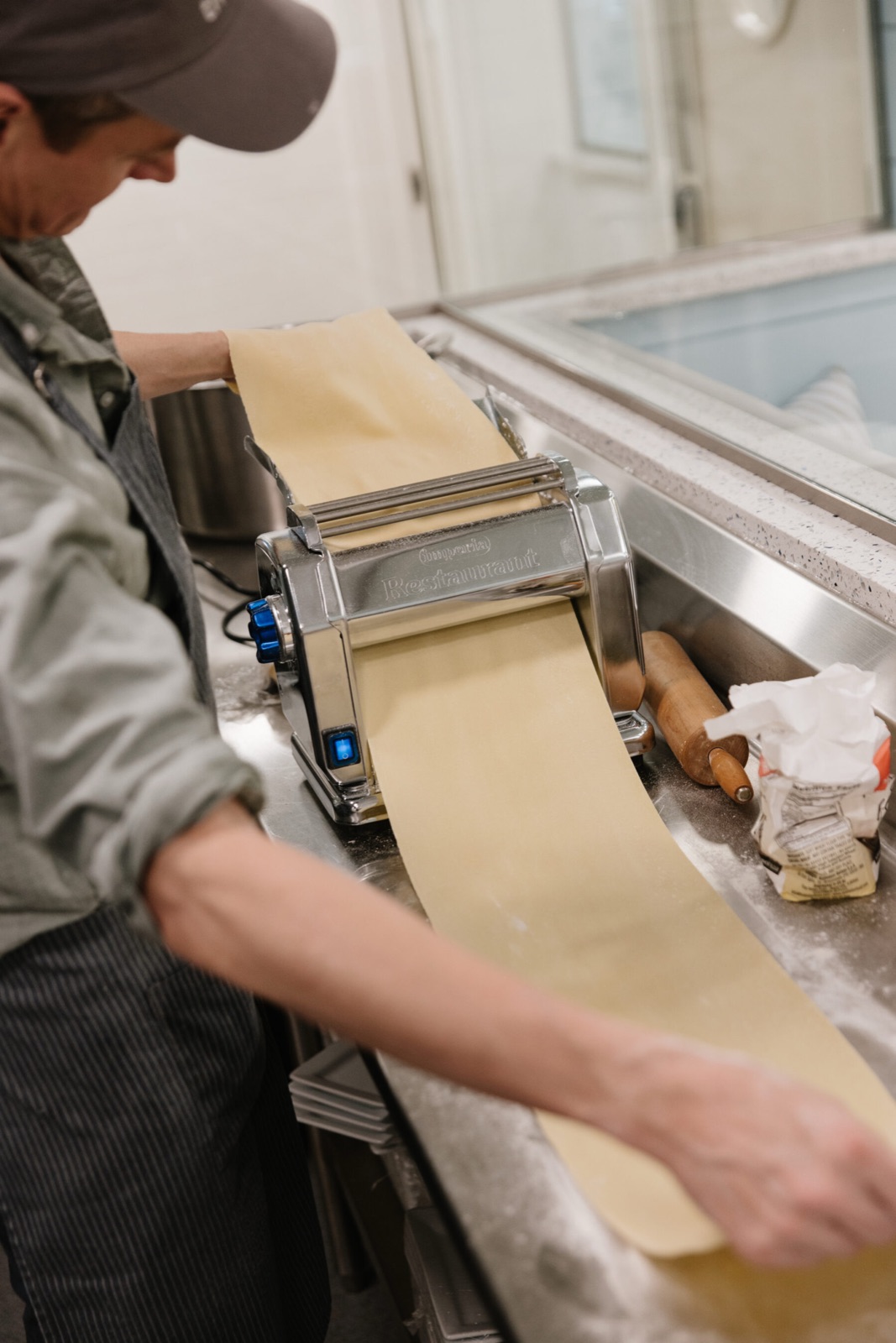 A Maker rolling fresh pasta through a pasta machine